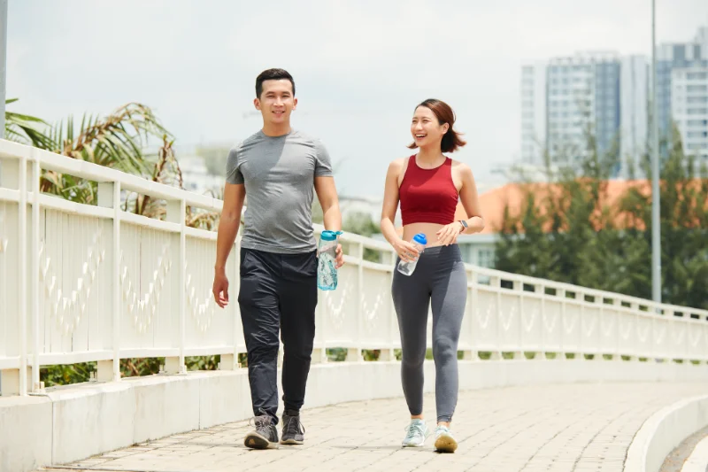 Sporty man and woman smiling together after workout, building fitness for their wedding day.