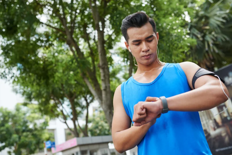Outdoor Cardio Training with Heart Rate Tracking for Smarter Results Male runner checking smartwatch for heart rate tracking during outdoor workout.