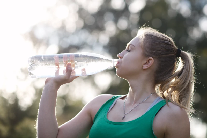 Stay Hydrated – Pre-Wedding Fitness Tip Woman drinking water outdoors after workout to stay hydrated before wedding