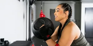Woman performing a medicine ball exercise at 9Round during a guided HIIT circuit training workout