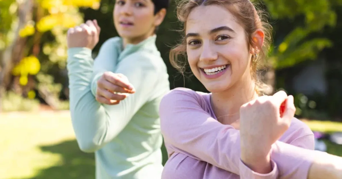 Two young people stretching arms outdoors before starting a daily workout