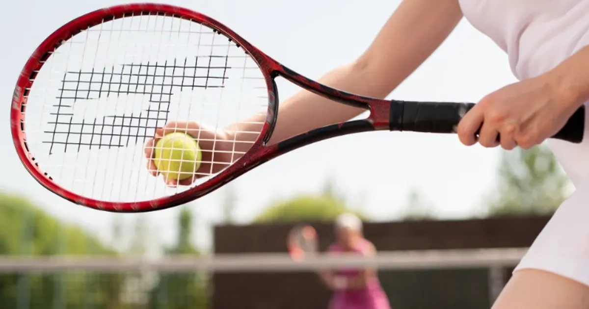 Close-up of a tennis player holding a racket and ball before serving during a match