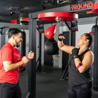 9Round trainer guiding a member through a speed bag workout during a holiday fitness session