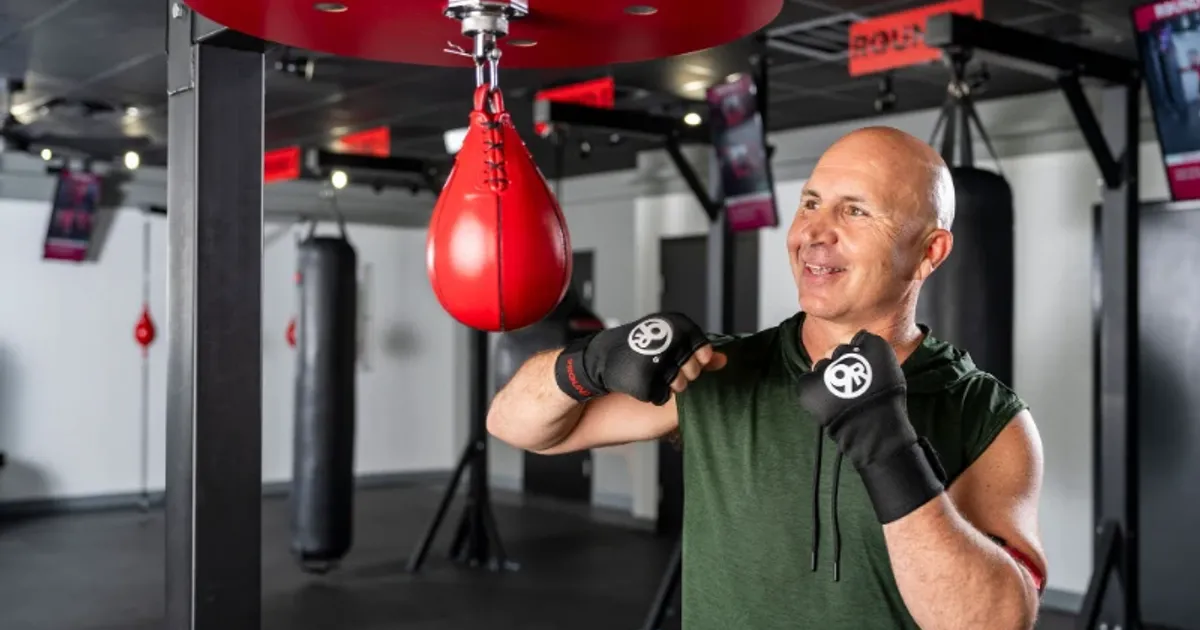 Man training on a red speed bag during a 9Round HIIT workout session