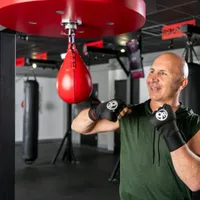 Man training on a red speed bag during a 9Round HIIT workout session