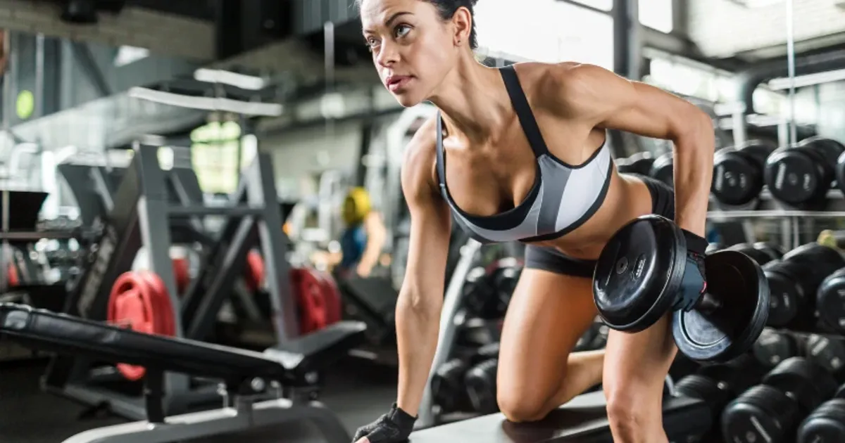 Woman performing dumbbell row exercise to build strength and muscle endurance at the gym