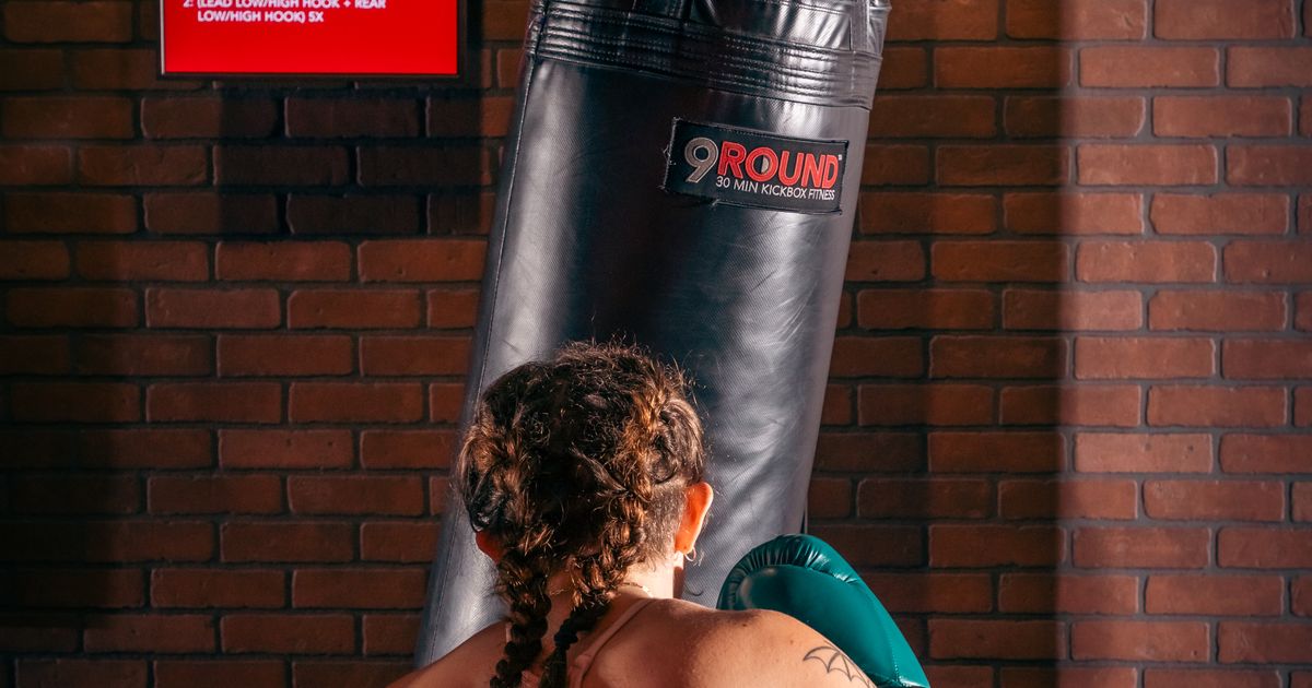 Member hitting heavy bag during HIIT kickboxing workout at 9Round Wicker Park on Division Street in Chicago