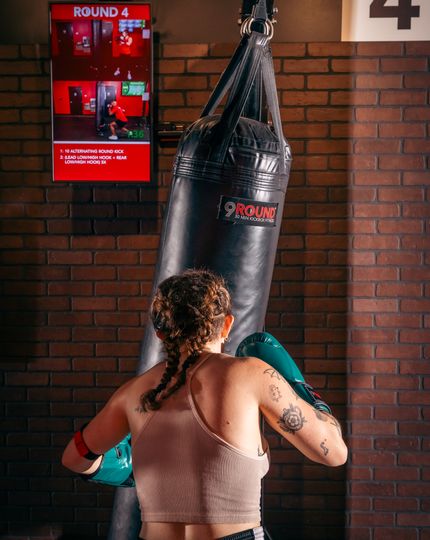 Member hitting heavy bag during HIIT kickboxing workout at 9Round Wicker Park on Division Street in Chicago