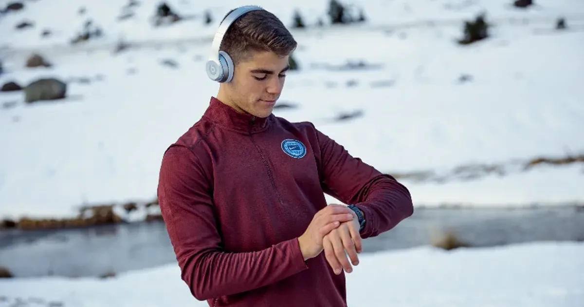 Man checking his watch during a winter workout routine to stay consistent with his fitness schedule