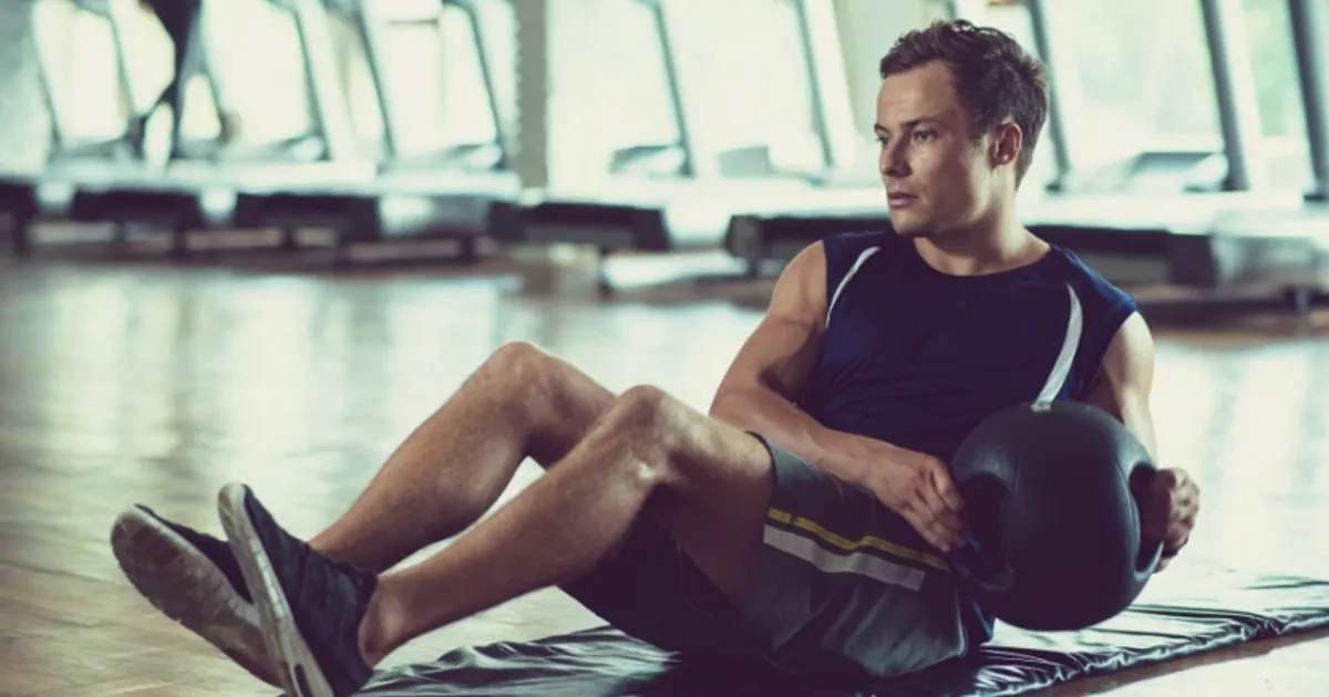 Man performing core exercises with a medicine ball during a gym workout session