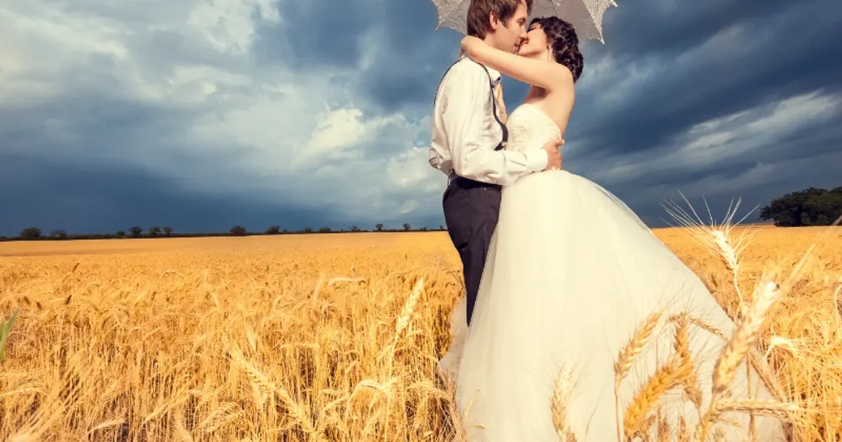Romantic wedding couple embracing in a golden wheat field before the stormy sky