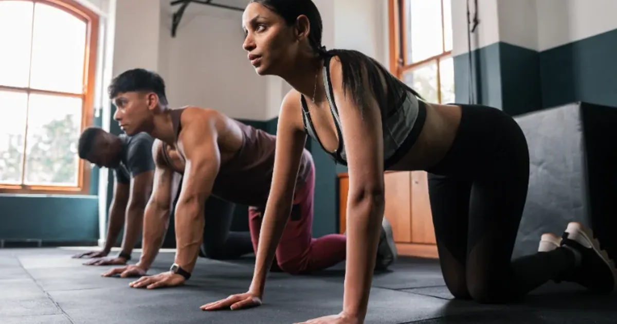 Group of people preparing for a floor bodyweight warm-up in a gym class