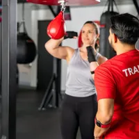 9Round trainer helping a member improve punching technique and workout form
