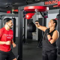 Trainer guiding a member through a punching workout for stress relief at 9Round Fitness