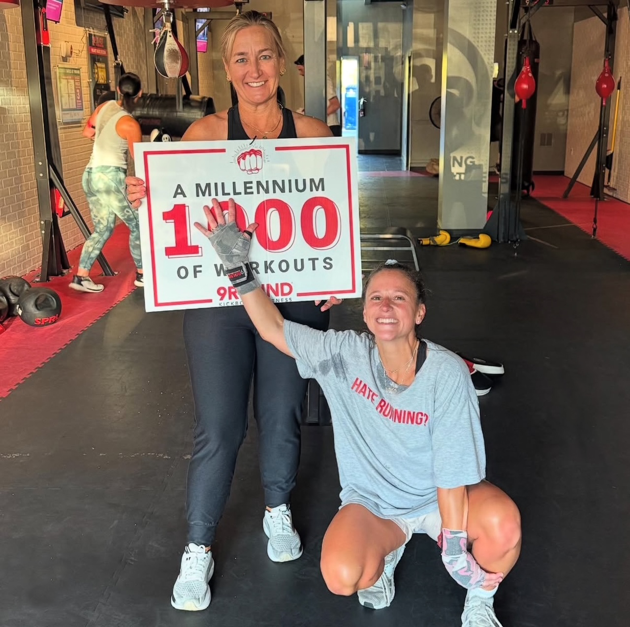 two women in a 9Round gym holding a 1000 workouts sign