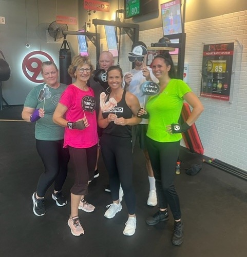 9Round owner posing with members at her studio” 
     style=