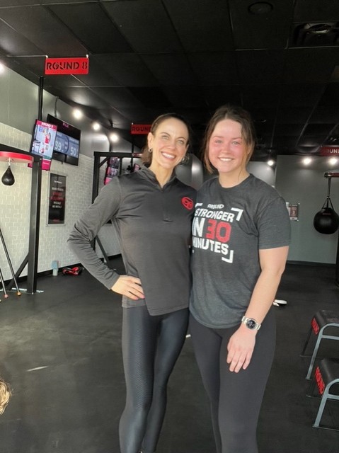 9Round owner posing for a photo with a member” 
     style=