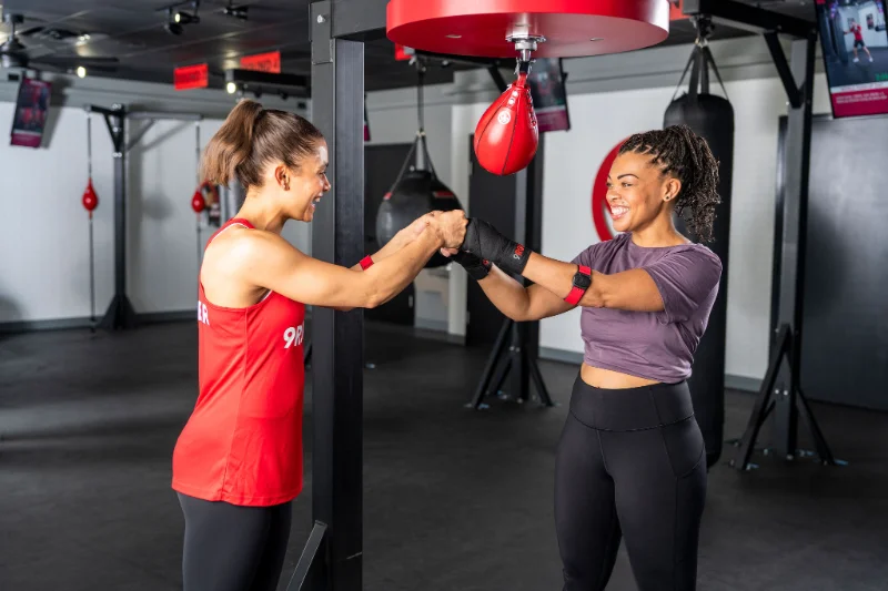 9Round trainer and member fist bump in front of a speed bag during workout.