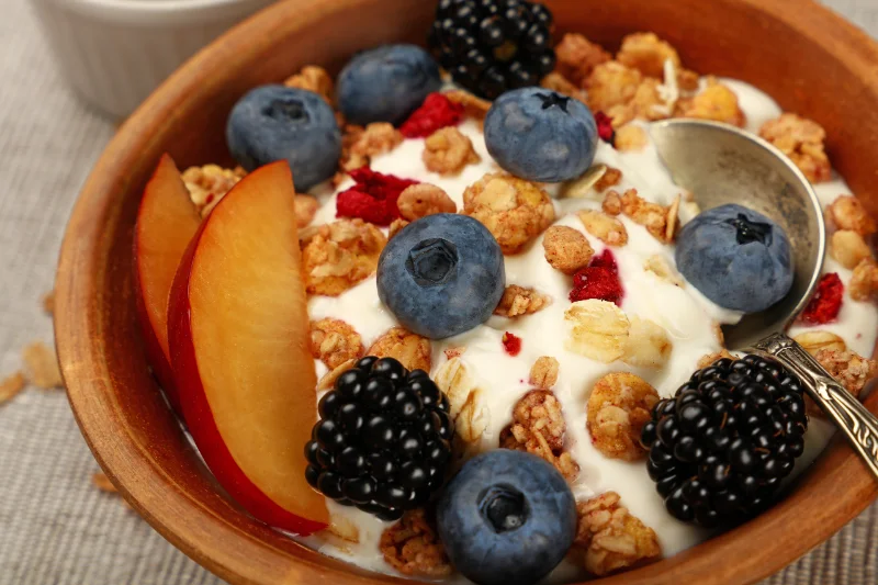 Bowl of Greek yogurt topped with blueberries, blackberries, peach slices, and granola for fast protein and antioxidants.