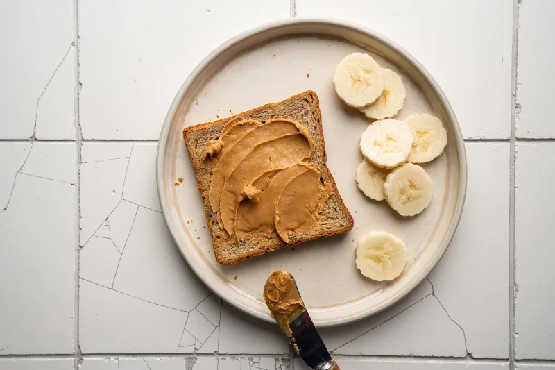 Whole grain toast with peanut butter and banana slices for quick carbs and healthy fats post workout.