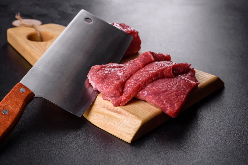 Fresh Raw Beef -- Carnivore Diet Meal Preparation Fresh raw beef slices on a wooden cutting board with a butcher knife for carnivore diet preparation
