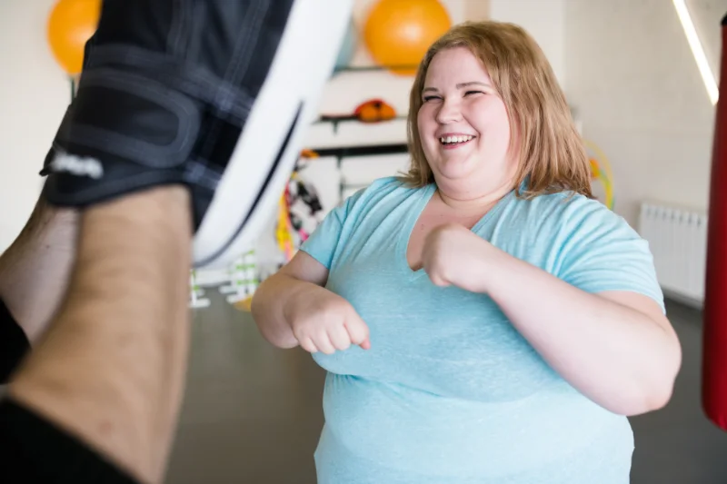 Smiling woman in a gym practicing boxing moves during a HIIT workout session