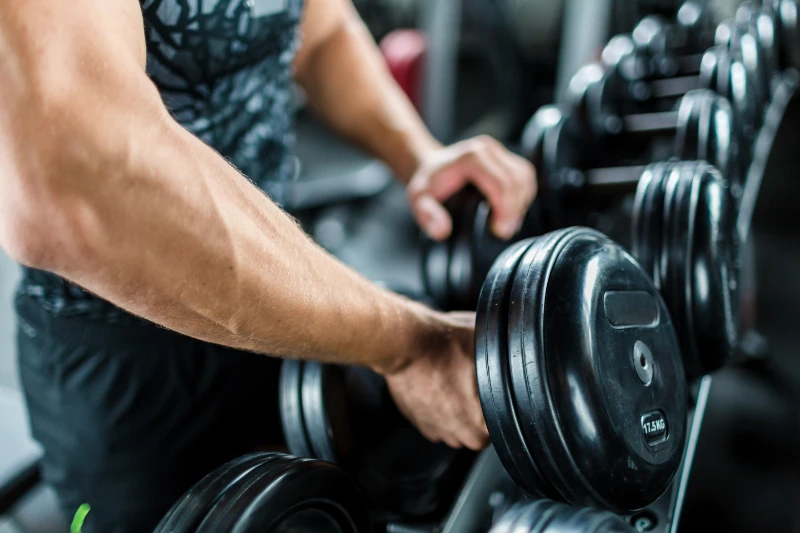 Man lifting heavy dumbbells during strength training workout at the gym