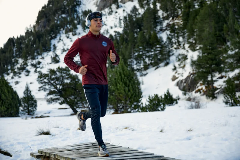 Man running outdoors in snowy weather to stay active and maintain winter fitness