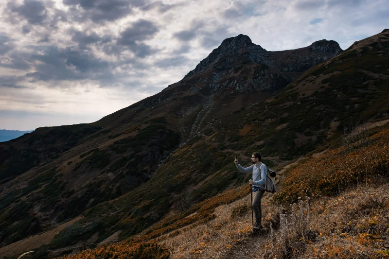 Mountain Hike on Autumn Trail Hiker taking a selfie on a mountain trail beneath a dramatic sky.