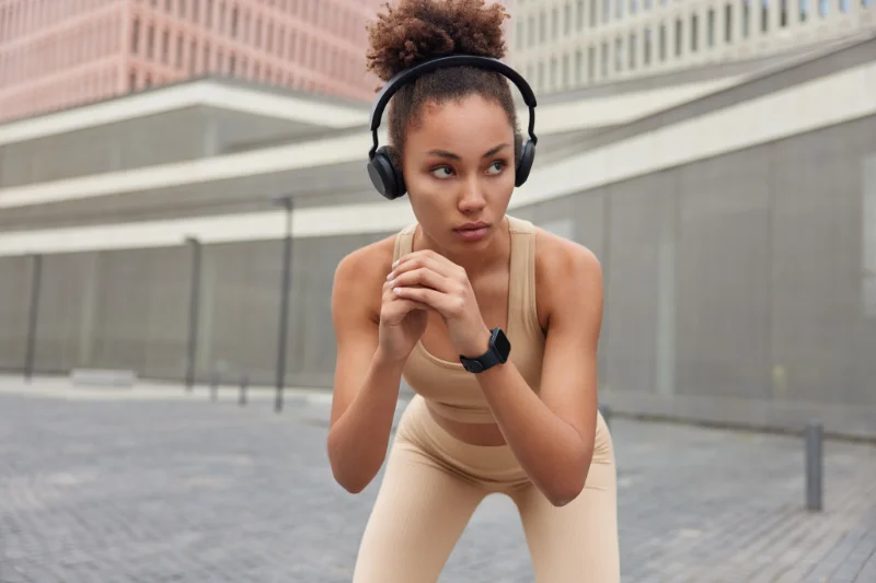 Woman performing squats outdoors with headphones on during bodyweight training.